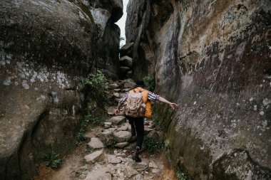 Dağlarda gezen adam. Sırt çantalı bir turist kayaya tırmanıyor.