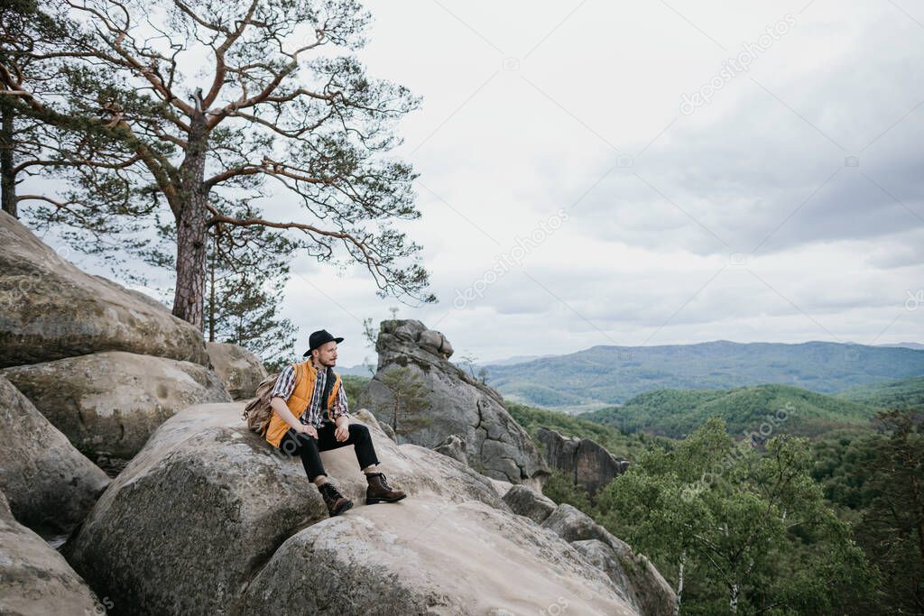 Hipster treveler standing alone on the edge cliff mountain and looking away. Adventure vacation, text spase