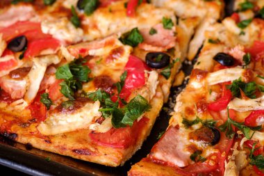Tavuk eti, jambon, domates, mozzarella peyniri, siyah zeytin ve maydanozlu taze ev yapımı pizza.