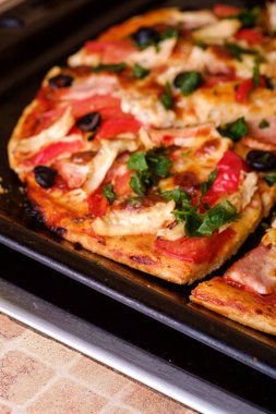 Tavuk eti, jambon, domates, mozzarella peyniri, siyah zeytin ve maydanozlu taze ev yapımı pizza.