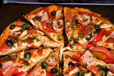 Tavuk eti, jambon, domates, mozzarella peyniri, siyah zeytin ve maydanozlu taze ev yapımı pizza.