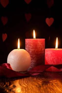 Üç mum ışığı, kurdeleli koyu romantik ışık arka planda aşk randevuları, sevgililer günü, seçici odaklanma.