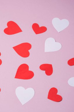 Kırmızı ve beyaz el yapımı kağıt kalpler pembe arka plan, açı görüşü, seçici odaklanma