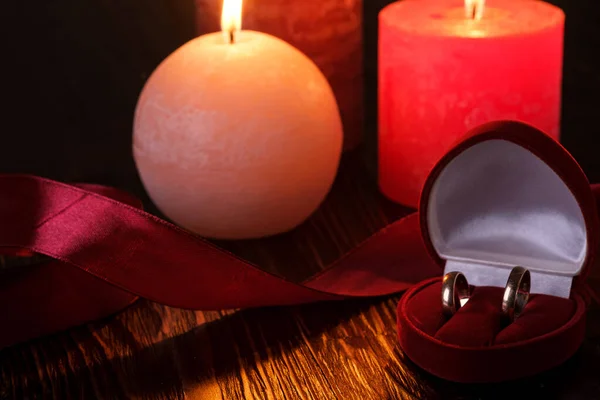 Kırmızı Hediye Kutusunda Iki Alyans Mum Işığı Koyu Romantik Işıkta — Stok fotoğraf