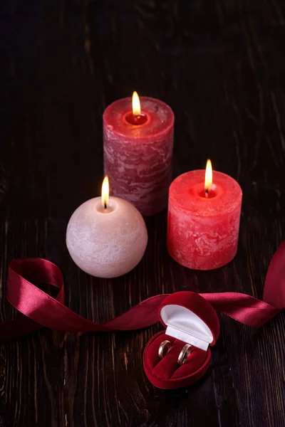 Dwie Obrączki Czerwonym Pudełku Trzema Woskowymi Świeczkami Wstążką Ciemnym Romantycznym — Zdjęcie stockowe