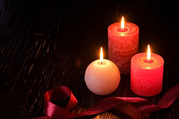 Three wax flame candlelight with ribbon in dark romantic light, love dating, Valentine\'s day, selective focus