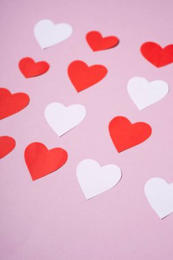 Kırmızı ve beyaz el yapımı kağıt kalpler pembe arka plan, açı görüşü, seçici odaklanma