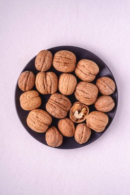 Ceviz yığını siyah tabakta, yarı soyulmuş fındıklı beyaz arka plan, üst manzara, sağlıklı yiyecek konsepti.