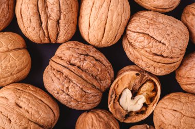 Ceviz yığını, yarı soyulmuş fındık, doku, üst görüş, sağlıklı yiyecek konsepti ile siyah tabakta.