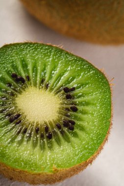 Kiwi fruits half sliced on vibrant plain white background, copy space, macro