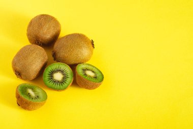 Kivi meyveleri yarı dilimlenmiş parlak sarı arka plan, kopyalama alanı, açı görünümü