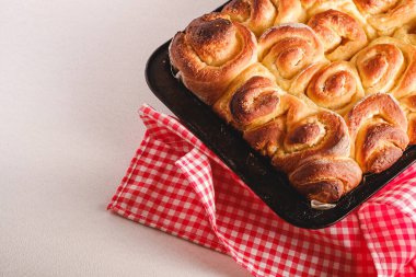 Sweet tasty homemade Rose buns rolls with sugar in baking sheet with red tablecloth hot and fresh, bakery for recipe book, angle view, copy space