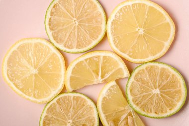 Taze limon ve limonlu narenciye dilimleri pembe tabakta, arka planda en az izole edilmiş, makro manzaralı.