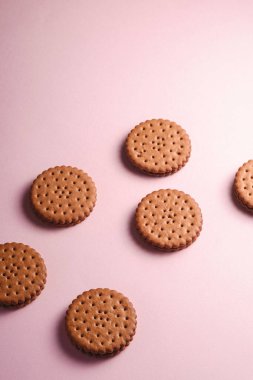 Kremalı çikolatalı sandviç, marketten tatlı yiyecekler, pembe pastel arka plan, açı manzaralı.