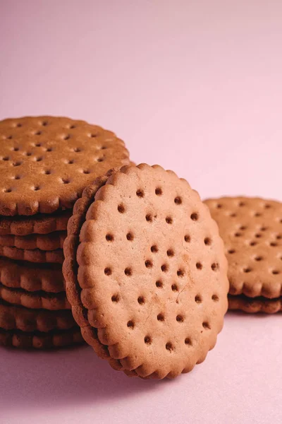 Chocolate sandwich cookie with cream, sweet stacked food from store, on pink pastel background, angle view