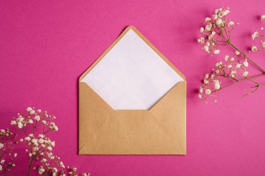 Beyaz boş kartlı Kraft kahverengi kağıt zarf, çigila çiçekleri, mor pembe arka plan, sahte boş harf.