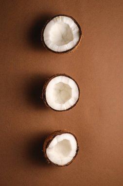 Kahverengi arka planda üç hindistan cevizi meyvesi, soyut gıda konsepti, üst görünüm