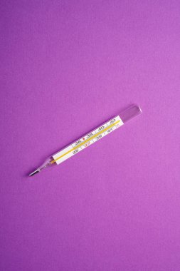 Mor arkaplan üzerine analog termometre, sağlık sigortası konsepti, antibiyotikler ve tedavi, üst görünüm kopyalama alanı