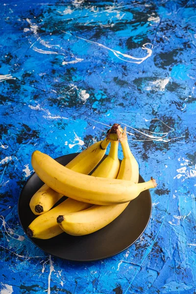 Бананові Плоди Чорній Пластині Синьому Текстурованому Фоні Кут Огляду Простору — стокове фото