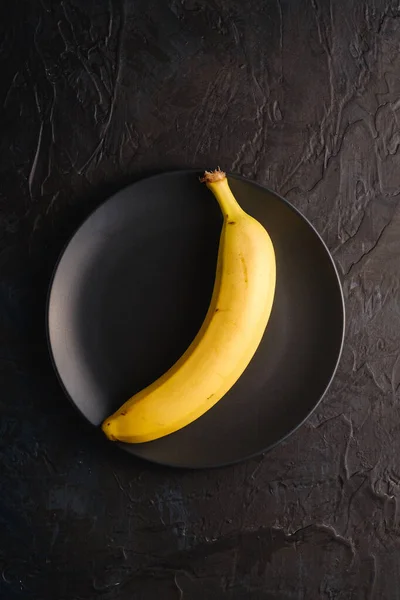 Single Banan Frukt Svart Platta Mörk Strukturerad Bakgrund Ovanifrån — Stockfoto