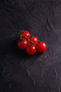 Çeri domates dalı, taze olgun organik sebzeler koyu siyah desenli arka plan, açı manzaralı.