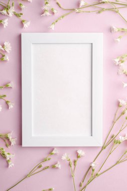 Pembe arka planda fare kulaklı civciv çiçekleri olan beyaz boş fotoğraf çerçevesi, üst görünüm kopyalama alanı