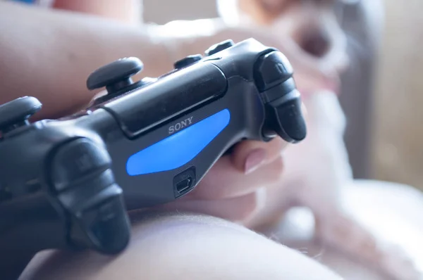 El momento del juego. Gamepad PS4 en las manos con un indicador azul — Foto de Stock