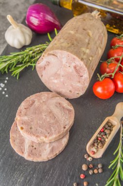 Ev yapımı jambonlu sosis, siyah tahtada dilimlenmiş, baharatlı ve aperatifli. Yan görünüm.