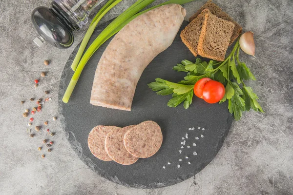Dilimlenmiş ciğer ezmesi, siyah tahtada otlar ve baharatlarla. Üst görünüm, yatay resim.