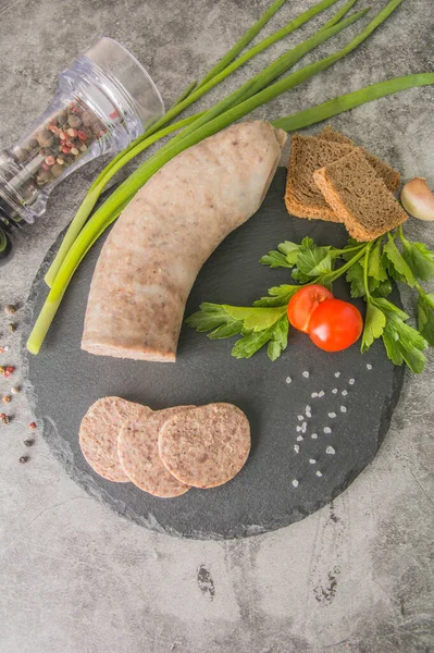Dilimlenmiş ciğer ezmesi, siyah tahtada otlar ve baharatlarla. Üst görünüm, dikey fotoğraf.