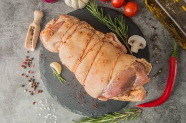 Salamura edilmiş çiğ domuz budu, sicimle kaplı, siyah tahtada baharatlar, üst manzara.