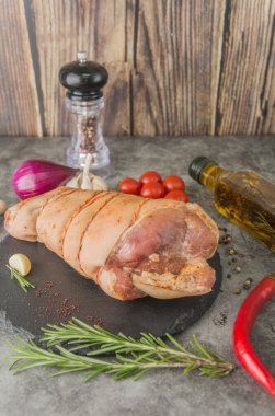 Salamura edilmiş çiğ domuz budu, sicimle kaplı, siyah tahtada baharatlar, yan görüş.