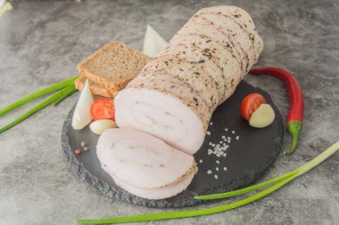 Baharatlarla kaplı büyük bir parça beyaz domuz yağı. Ekmek ve baharatlarla kaplı siyah bir sayfada.