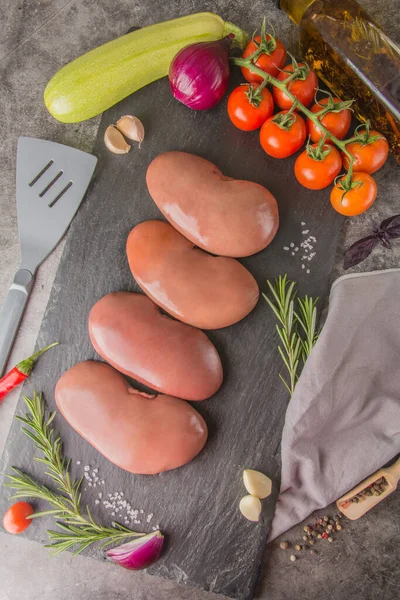Raw pork kidneys on black slate with spices and seasonings in a butcher's shop, top view, vertical photo — Stock Image Raw Pork Kidneys Black Slate Spices Seasonings Butcher Shop Top Stock Picture