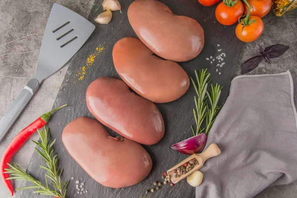 Raw pork kidneys on black slate with spices and seasonings in a butcher's shop, top view — Stock Image Raw Pork Kidneys Black Slate Spices Seasonings Butcher Shop Top Royalty Free Stock Images