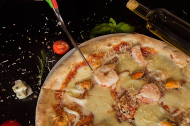 Pizza makasıyla pizza kesmek. Siyah bir masada - üst görünüm.