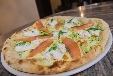 Somon pizzası - yakın plan, parlak bir masanın üzerinde.