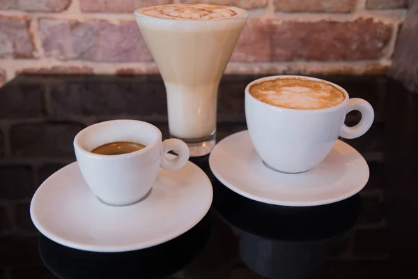Üç çeşit kahve - latte, americano ve espresso - siyah ayna arka planında.