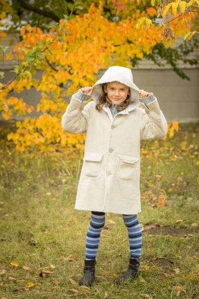 Brunette fille dans un manteau léger avec une capuche en jaune congé d'automne — Photo