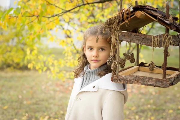 Brünettes Mädchen im hellen Mantel mit Kapuze im gelben Herbsturlaub — Stockfoto