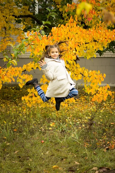 Morena chica en un abrigo ligero con una capucha en amarillo permiso de otoño — Foto de Stock