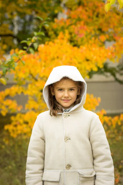 Brunette fille dans un manteau léger avec une capuche en jaune congé d'automne — Photo