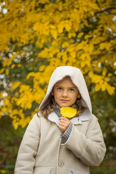 Brunette fille dans un manteau léger avec une capuche en jaune congé d'automne — Photo