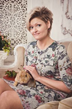 W oturan gri elbiseli kısa sarı saçlı genç kadın modeli