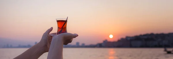 Tè in vetro tradizionale turco sul palmo della mano femminile all'alba agai — Foto Stock