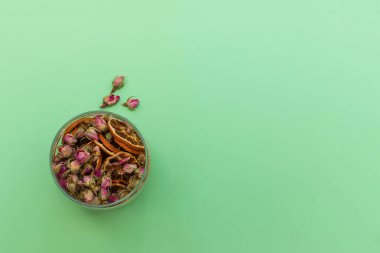 Kavanoz dolusu kurutulmuş portakal ve tomurcuk tomurcukları. Çaya ya da dekora katkı sağlamak için kullanılır. Yeşil arkaplandaki üst görünüm. Metin için yeri olan resim