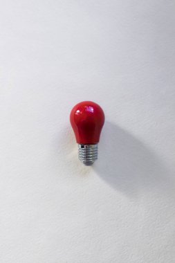 Beyaz arkaplanda küçük kırmızı ampul üst görünümü. Fikir kavramı, düşünce ortaya çıkıyor. Kopyalama alanı olan en üstteki görüntü