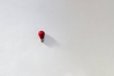 Beyaz arkaplanda küçük kırmızı ampul üst görünümü. Fikir kavramı, düşünce ortaya çıkıyor. Kopyalama alanı olan en üstteki görüntü
