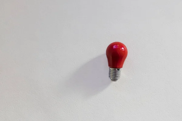 Small red light bulb top view on white background. Concept of idea, thought arising. Top view picture with copy space