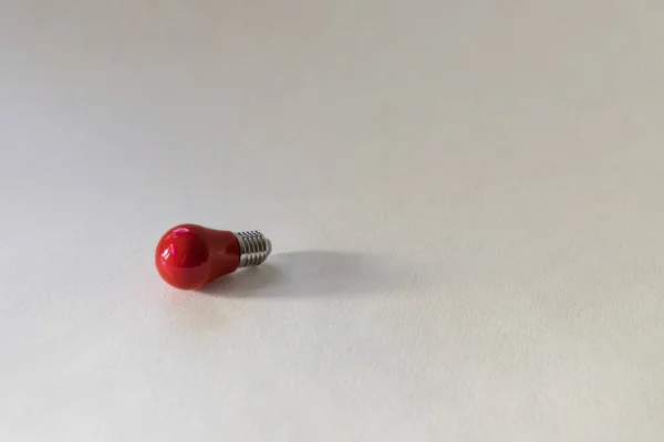 Small red light bulb top view on white background. Concept of idea, thought arising. Top view picture with copy space